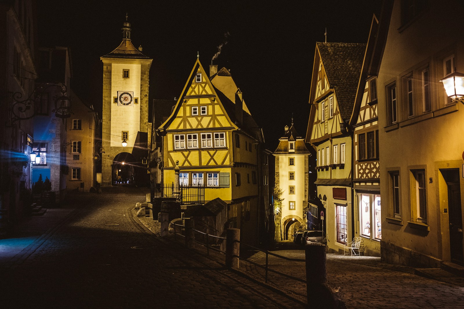 a street at night with a clock tower in the background