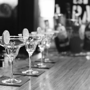 Monochrome margarita glasses on a bar counter with lemon slices, creating an elegant atmosphere.